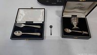 Cased fork and spoon, cased goblet with feeding spoon, and loose demitasse spoon
