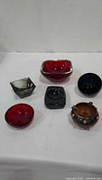 Group of six glass ashtrays in various colors and shapes