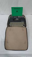 Typewriter inside open case with green sheet in platen