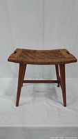 Full view of wooden stool with woven seat