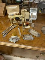 overview of entire lot on wooden surface showing grooming tools, perfumes, jewellery box, comb, mirror