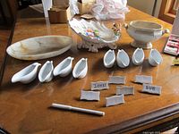 Full lot view showing sauce boats, place markers, fruit dish, marble plate, pottery dish, boxed place cards and pen