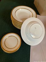 Stacked soup bowls and bread & butter plates showing gold rim design