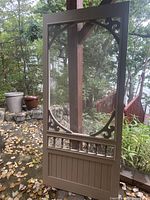 full front view of painted wood screen door showing screen, decorative scrollwork, red spindles, lower panel