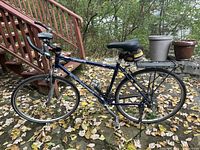 Full left side view of Rocky Mountain Latitude bike showing frame, wheels, rear rack, saddle bag, bell, light, cycle computer