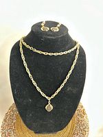 Necklace displayed doubled on bust with matching earrings on top