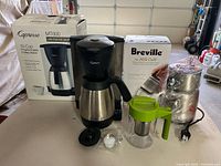 Group shot displaying Capresso coffee maker with carafe, Breville Milk Café with box, Takeya tea pot, accessories visible