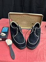 Shoes front view with box lid open and shoe brush visible