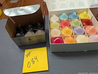 Open box showing 6 monochrome candles and open box of 16 assorted colours