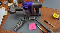 Dyson handheld vacuum, brush tool, charger on table