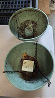 Top view of both green plastic hanging planters with chains attached