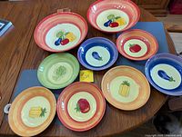 All nine ceramic bowls laid out showing vegetable motifs and colour rims