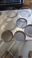 overview of 3 glass pie plates and 4 perforated pizza pans on table
