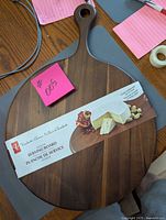 Full view of round acacia board with handle and packaging band