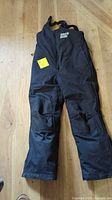 Full view of black Pro Star snowmobile bib pants laid flat