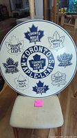 Full view of round Toronto Maple Leafs wood sign on chair