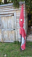 Umbrella folded and standing beside wooden shed