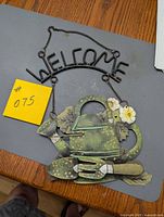 Full view of metal watering can welcome sign showing design and chain