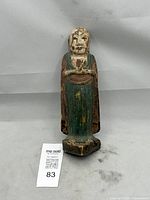 Full view of carved wooden Buddha figure showing overall form, paint remnants, and size reference