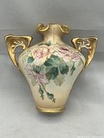 Front view of porcelain vase showing floral painting and gilt handles
