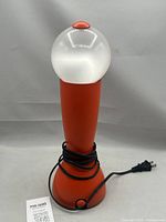 Front view of red desk lamp with spherical diffuser and power cord