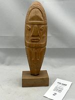 Full front view of carved wooden figure on base