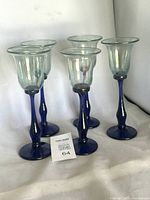 Front view of five Rick Strini wine glasses showing cobalt stems and iridescent bowls