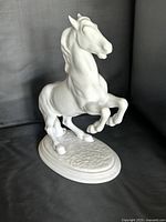 Front left view of porcelain rearing horse on oval base