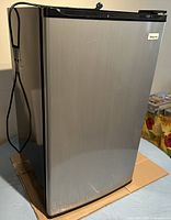 Closed view of the Magic Chef mini fridge with black sides and stainless steel door finish.