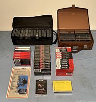 Wide shot showing all items included in the lot: 36 blank audio cassette tapes packaged and loose, two different cassette storage cases with tapes inside, a TDK dry type head cleaner cassette in original packaging, a Realistic 3-way cassette cleaning kit unopened, and some empty cassette sleeves.