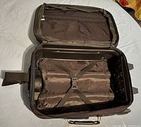 Open view of suitcase showing interior straps and zippered compartment inside lid.