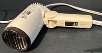 Side view of cream-colored Solaray Foldin’ PRO 1200 compact travel hairdryer with folded handle and visible two-speed switch.