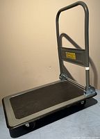 Compact utility dolly with handle up, showing entire loading platform and wheels.