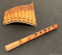 Mini pan flute alongside small recorder with painted leaf and swirl patterns, showing both items in the lot