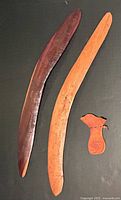 Two boomerangs and kangaroo leather pouch displayed on dark surface showing size and material details