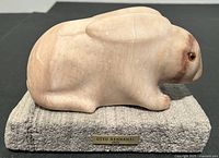 Side view of the hand-carved rabbit sculpture on its pumice tile base including the artist plaque.