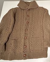 Front view of men's XL light brown hand-knit cardigan sweater with button front, high collar, cable knit pattern and two pockets.