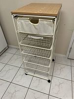 Front view of the IKEA Antonius storage unit showing the fabric drawer and wire baskets underneath with arborite top.