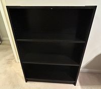 Front view of IKEA Billy bookcase showing all three shelves and black wood-grain finish.