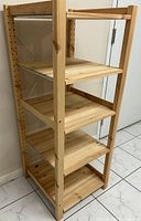 Front-side view of natural solid pine shelving unit with five adjustable shelves and visible shelf support peg holes.