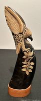 Side view of the eagle sculpture showing carved feathers and leaf design on buffalo horn base with teak wood stand.