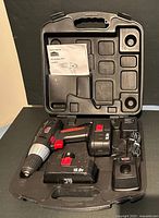 The open black hard plastic carry case with JOBMATE cordless drill, two batteries, charger and manual inside compartments.