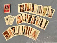 Photo showing spread of playing cards featuring vintage pin-up art and original box with front design.