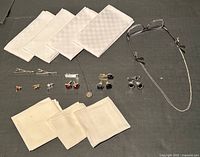 Photo showing the full assortment of men's accessories including tie pins, tie clips, cufflinks, seven white handkerchiefs, glasses with retainer chain, and pendant on chain.