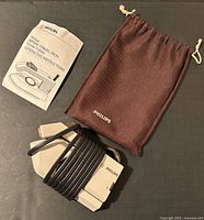Philips travel iron, operating instructions and drawstring pouch displayed on dark surface.
