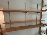 Three solid pine shelves mounted on adjustable vertical metal wall tracks.