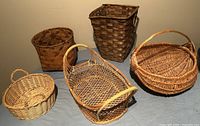 All five wicker baskets arranged on a cloth surface to show size and weave details.