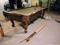 Full view of Connelly pool table with cues on floor