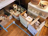 Overview of multiple boxes and bins containing Franciscan Apple dinnerware pieces