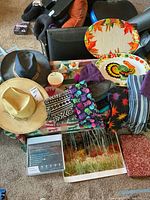 Overview of lot showing hats, platters, scarves, bowl, figurines, framed print, boxed electronic item